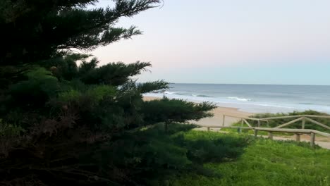 Weitwinkelaufnahme,-Die-Einen-Unerkannten-Surfer-Zeigt,-Der-Bei-Sonnenaufgang-Am-Guincho-Strand-Allein-Inmitten-Von-Klippen-Das-Meer-Beobachtet