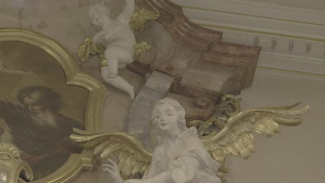 sculpture of a white angel with golden wings on a baroque altar