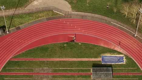 aerial view following solo runner on red running track in parliament hill london oval landmark