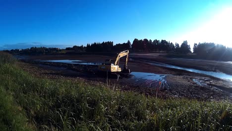 la excavadora amarilla trabaja con un balde para limpiar lodos de lodo y escombros del fondo del río drenado-2