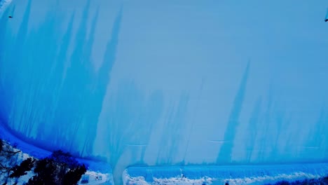 parque cubierto de nieve invernal con caminos helados hechos por el hombre conectados a una enorme pista de patinaje al aire libre en el centro de la ciudad rodeada de bancos para hogueras para cambiarse los zapatos al atardecer con sombras de árboles out1-2