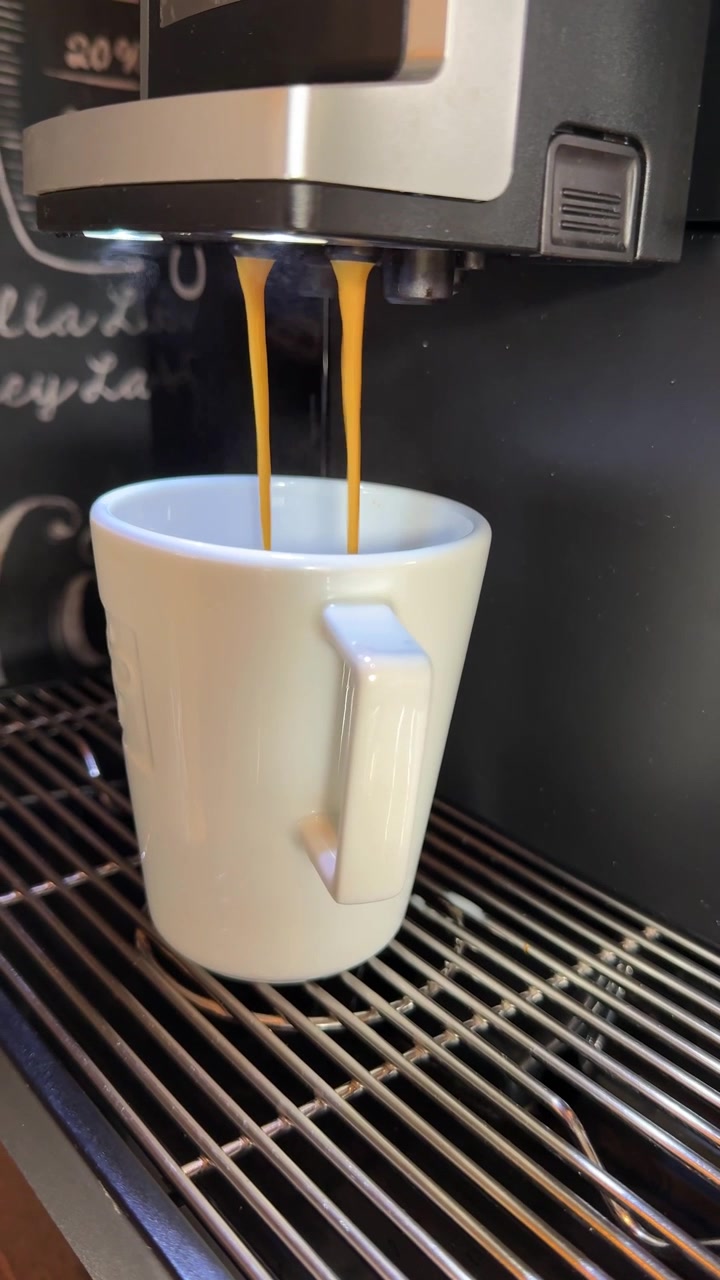 Café recém-preparado servido em um copo de papel para viagem dentro de um café. Ideal para cultura do café, cafés, hotelaria, estilo de vida, rotinas matinais e projetos relacionados a bebidas. Close-up vertical.