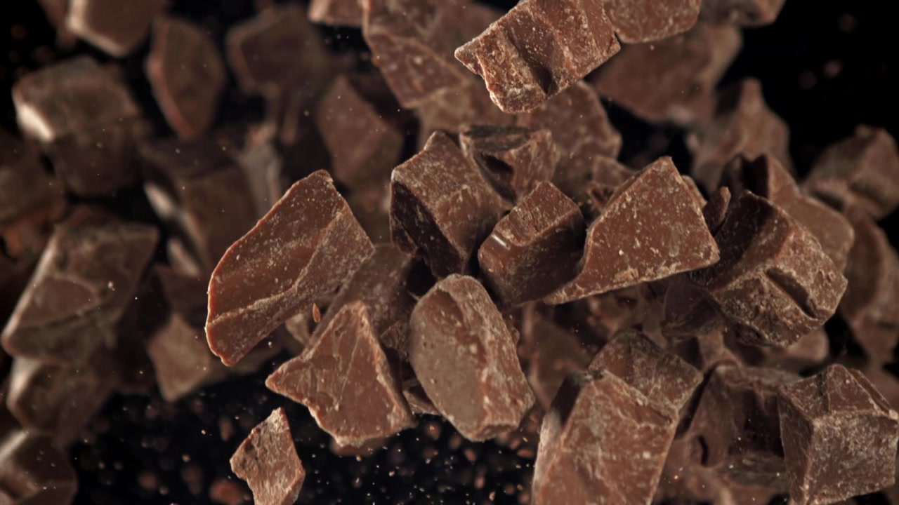 Pezzi di cioccolato che volano in alto al rallentatore su sfondo nero