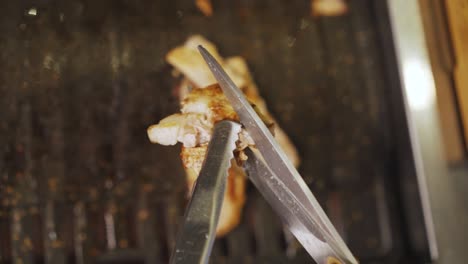 samgyeopsal - person cutting grilled pork belly with scissors