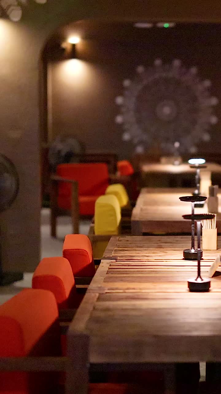 Ristorante vuoto con illuminazione calda, sedie colorate e tavoli in legno.