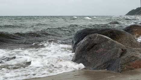 waves rolling and crashing into rocky shore on overcast day