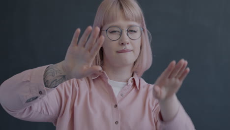 Woman with Pink Hair and Glasses Interacting with an Invisible Object