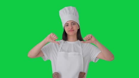 una mujer india molesta chef profesional pulgares hacia abajo pantalla verde
