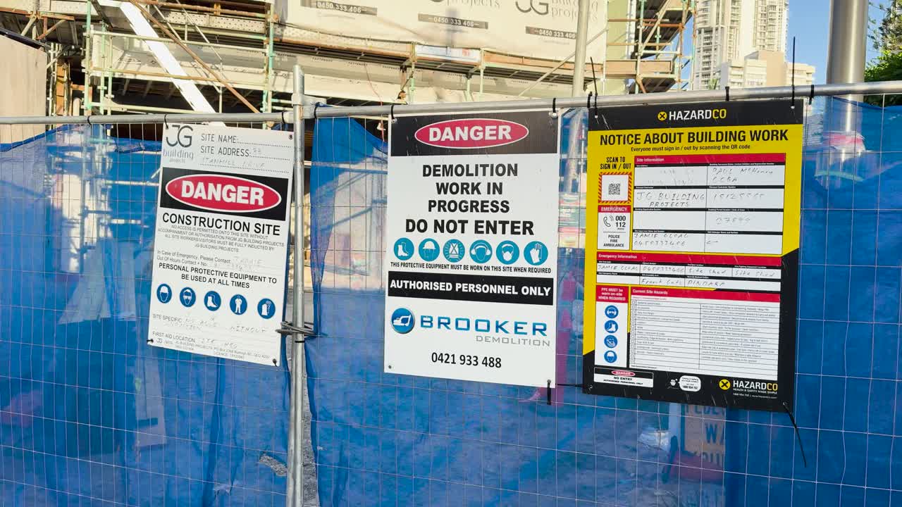 A series of safety signs at a construction site in Surfers Paradise, Queensland, emphasizing caution and safety protocols