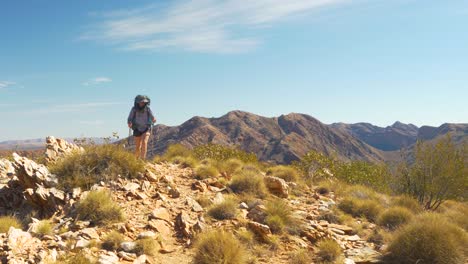 hiker approaches camera along rugged mountain ridge, central australia