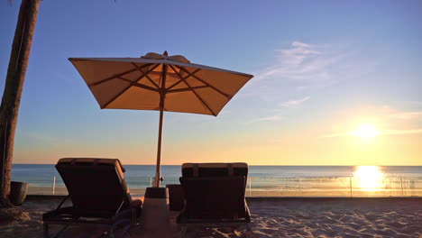 Two-Deckchairs-Under-Parasol-In-Tropical-Beach-At-Sunset