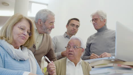 group of senior people with teacher looking at laptop screen