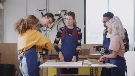 multi-cultural team of trainees in workshop assembling hand built bicycle frame together