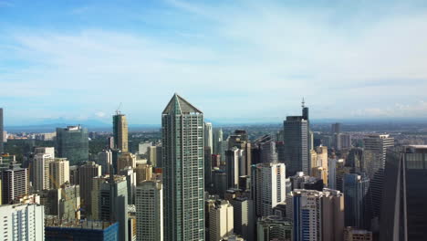 aerial view backwards in front of the makati cityscape, sunny evening in manila