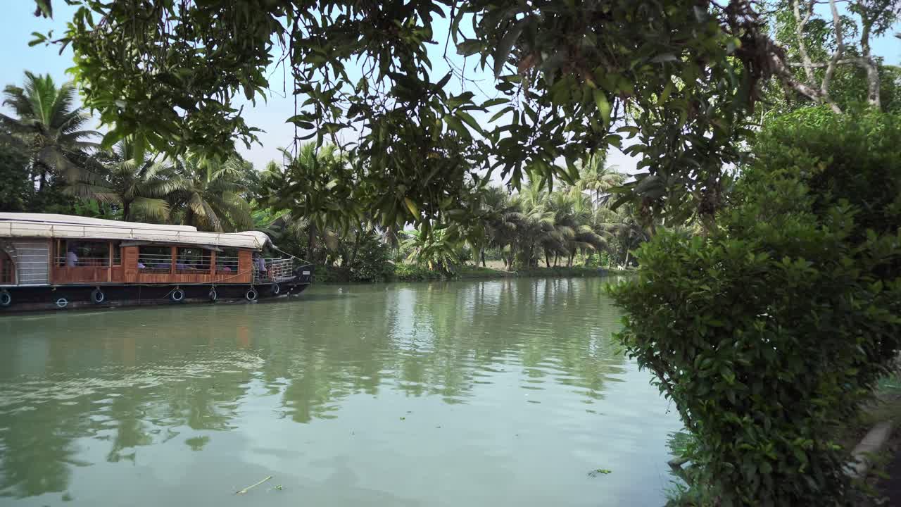 kerala barco casero tradicional pasa a través de las aguas remotas de kerala con asentamientos locales en los lados del canal