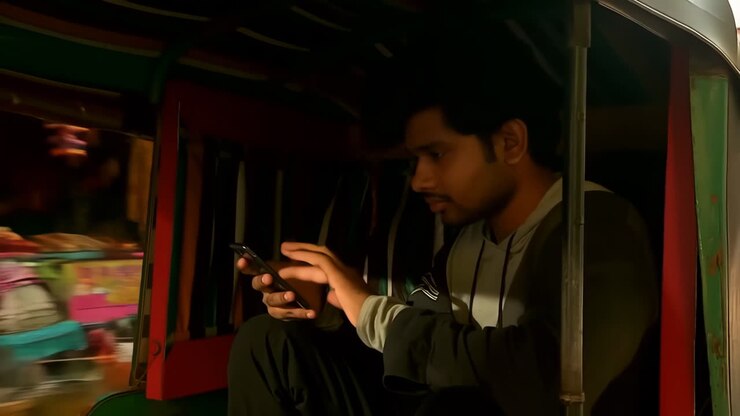 Man using smartphone inside an auto-rickshaw at night