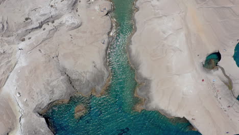 Aerial:-Beautiful-rising-top-down-view-of-Sarakiniko-beach-in-Milos-island,-Cyclades,-Greece-with-emerald-crystal-water-during-noon