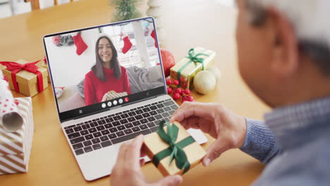 biracial man with gift having laptop video call with happy biracial woman