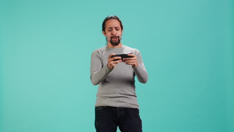 man playing videogames on smartphone, celebrating after being victorious