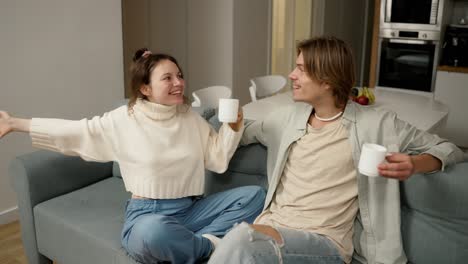 Closeup-smiling-couple-drinking-tea-at-home-together,-happy-woman-talking-emotionally