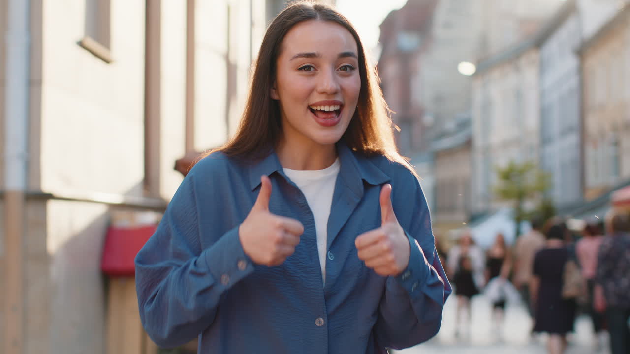 Young woman showing thumbs up like sign positive something good positive feedback in city street