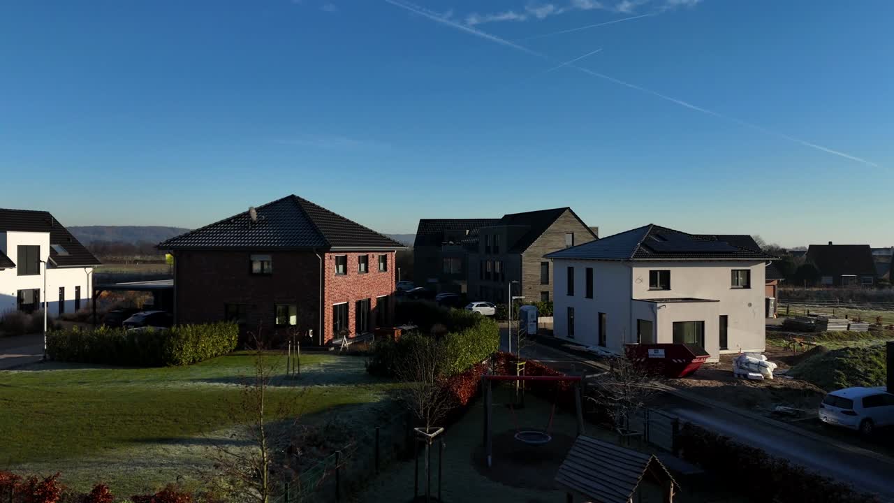 disparo de drone en ascenso de un nuevo barrio desarrollado cerca del campo. día soleado de invierno con villas urbanas y casas unifamiliares en alemania. campos agrícolas rurales en la distancia. disparo ancho.