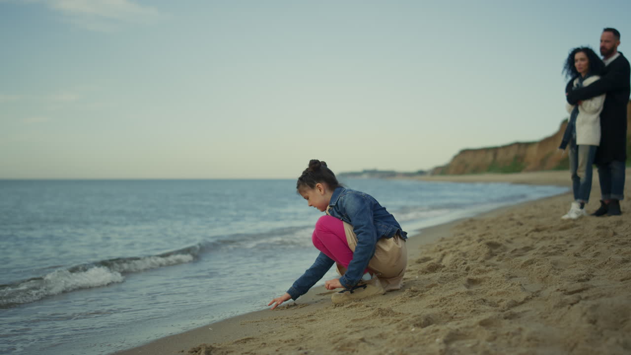 una familia joven relajándose de vacaciones juntos en la playa al aire libre.