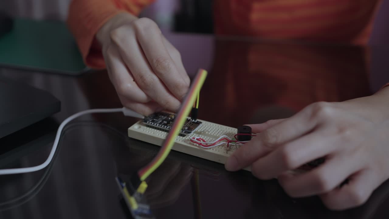 Hand of woman plugging a pin on an electronic circuit board with an open-source hardware and software microcontroller board
