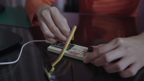 hand of woman plugging a pin on an electronic circuit board with an open-source hardware and software microcontroller board