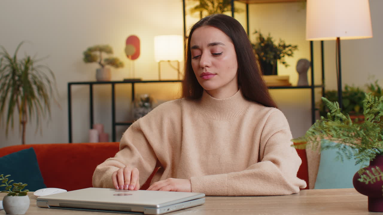 Bored sleepy business woman worker works on laptop leaning on hands falling asleep at home table