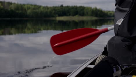 kayaker paddling across a peaceful lake on a cloudy day