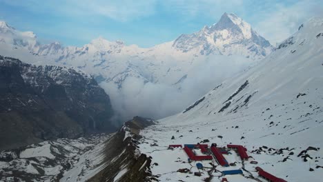 Filmische-Luftaufnahme-Des-Annapurna-Basislagers-Auf-Einem-Schneebedeckten-Berghang-Mit-Dem-Machapuchare-Gipfel-Im-Hintergrund