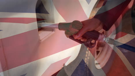 union jack flag waving over hand of african american man refueling car