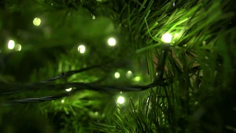 Close up view inside a christmas tree lights glowing, indoor livingroom during holidays