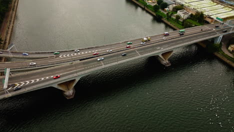 coches de tráfico que circulan por la carretera a través de un amplio puente fluvial en hongkong, china