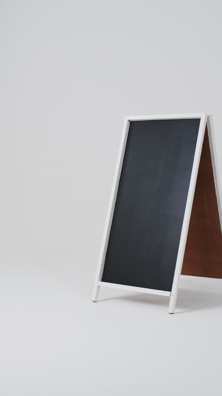 Vertical video of blackboard sign on white stand with copy space on white background