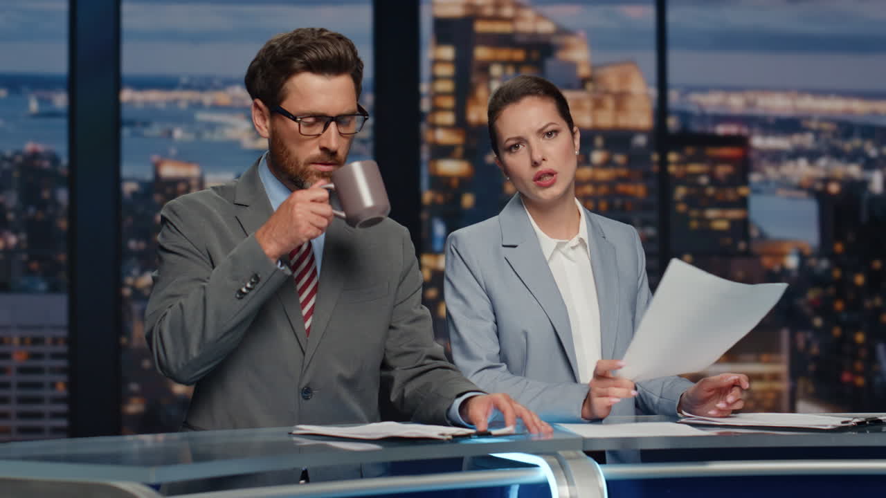 anfitriones serios transmitiendo noticias en primer plano en el estudio. una pareja de presentadores de noticias hablando