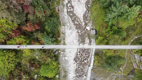 annapurna circuit trek in nepal - tourists hikers walking on a narrow bridge over the forest river