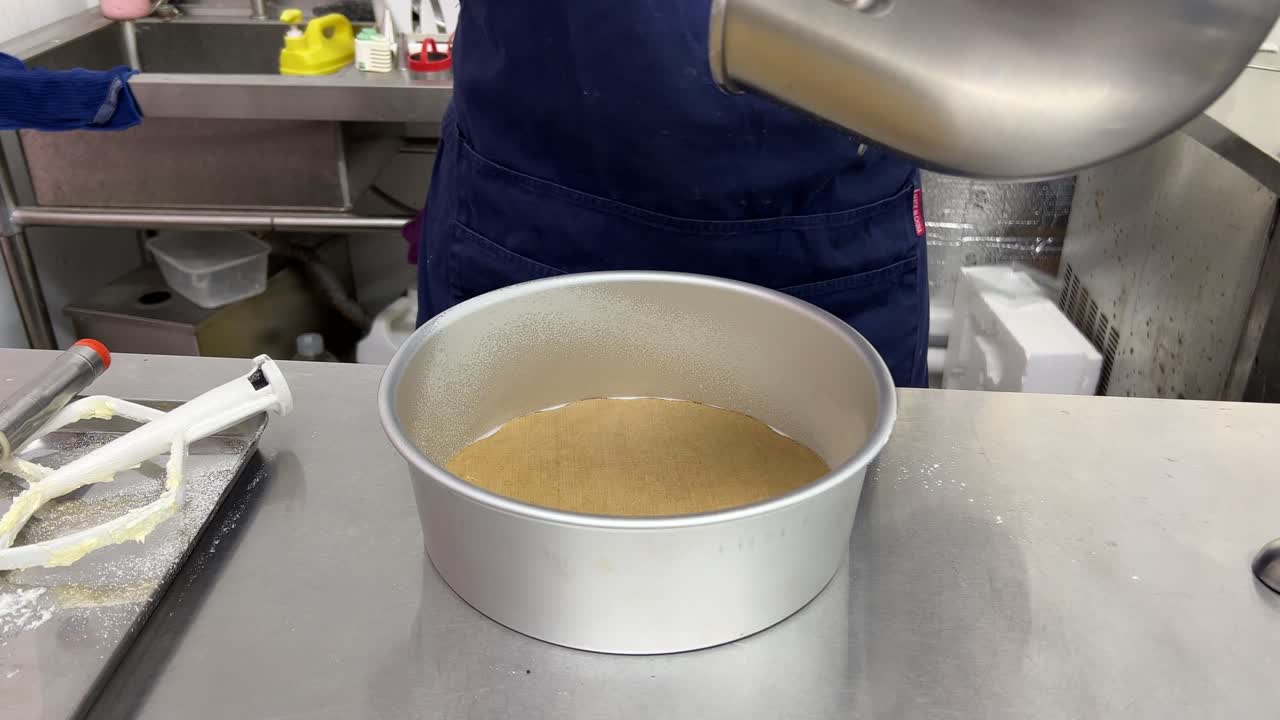 Baking paper placed at the bottom of cake mould, professional pastry chef scarping matcha cake mixture using spatula and pouring into baking mould, close up shot of delicious cake making in progress