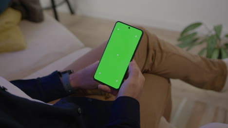 detail of male hand taking cell phone with green chroma screen for graphic insertion