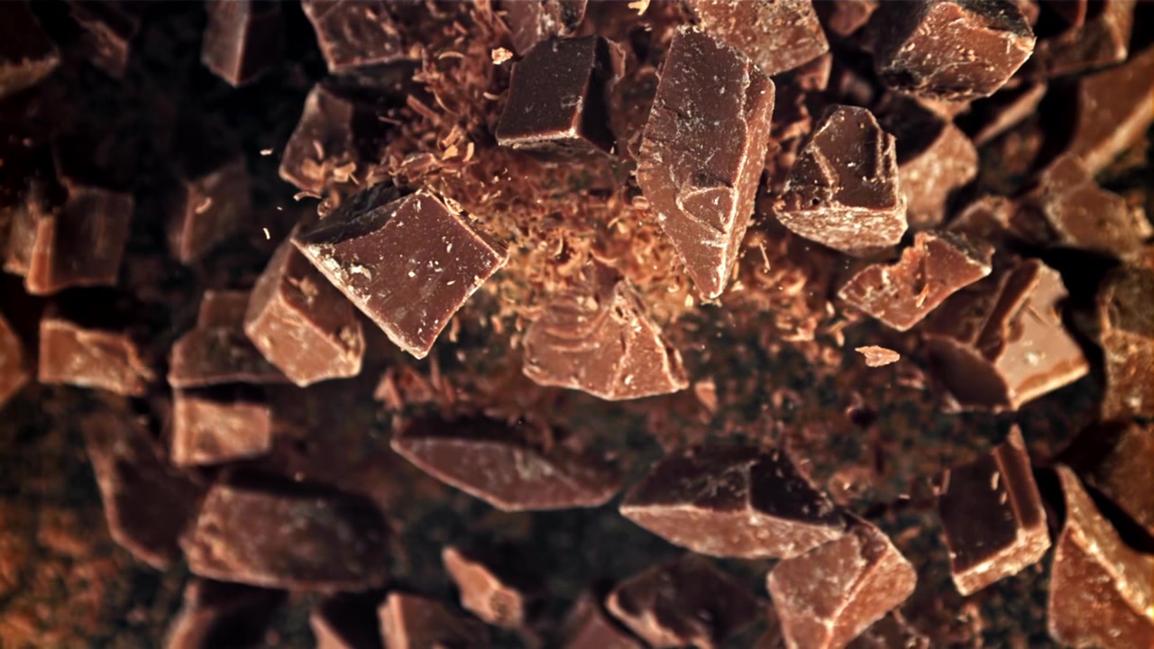 Movimento rallentato di pezzi e scaglie di cioccolato che cadono e si disperdono