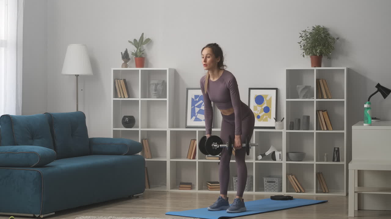 entrenamiento de fitness en el hogar mujer adulta está haciendo inclinaciones con pesas en las manos entrenamiento en la sala de estar estilo de vida saludable y ejercicios de culturismo