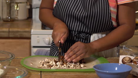 African-American-Woman-in-Apron-Finely-Chops-Mushrooms-in-Home-Kitchen