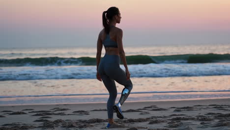 woman with a prosthetic leg walking on the beach at sunset