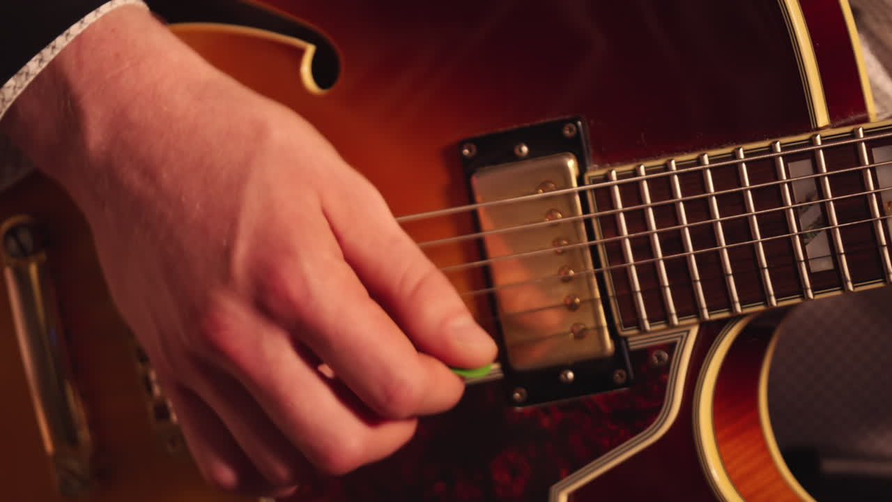 Persona che suona una chitarra elettrica con un plettro. - primo piano