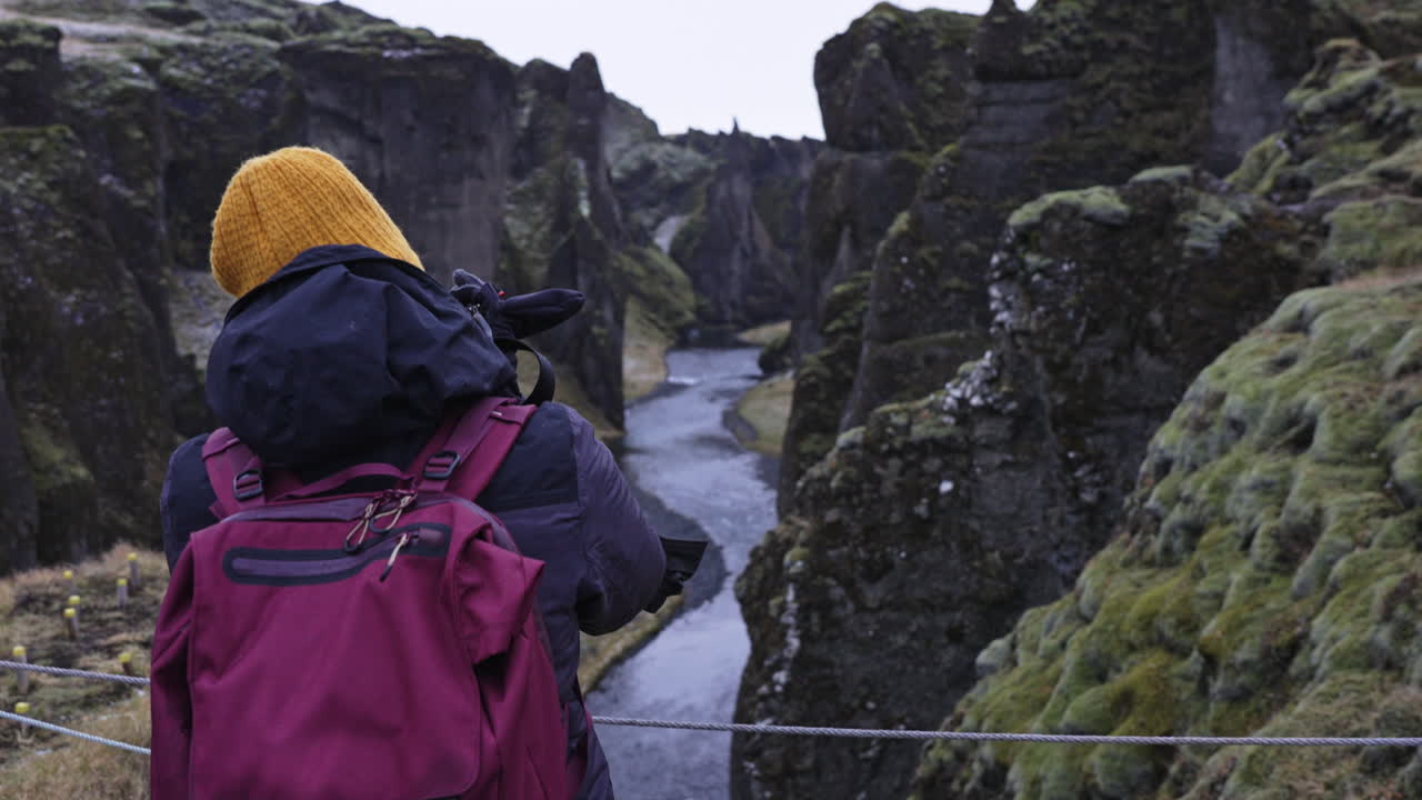 turista tomando fotos en el cañón fjadrargljufur en islandia
