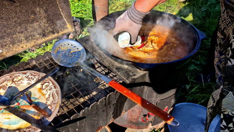 outdoor cooking scene with a pot of stew simmering on a rustic stove under bright sunlight