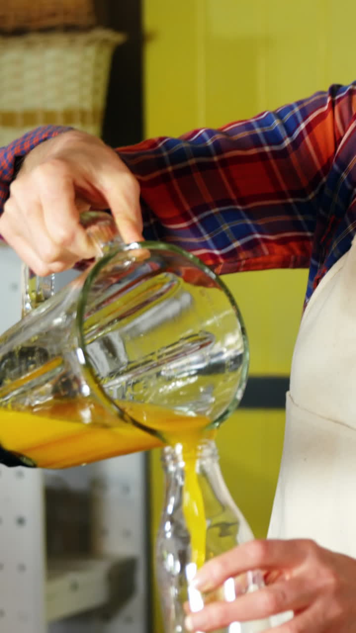 Mujer vertiendo zumo de naranja en una botella