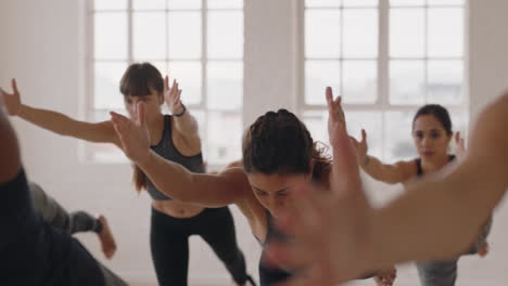 Hermosa-Mujer-Caucásica-De-Yoga-Practicando-Meditación-En-Pose-Guerrera-Con-Un-Grupo-De-Mujeres-Multirraciales-Disfrutando-De-Un-Estilo-De-Vida-Saludable-Haciendo-Ejercicio-En-Un-Gimnasio-Al-Amanecer.