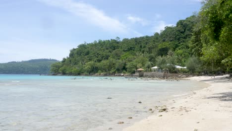 Picturesque-tranquil-tropical-sandy-beach,-ocean-water-still-and-calm